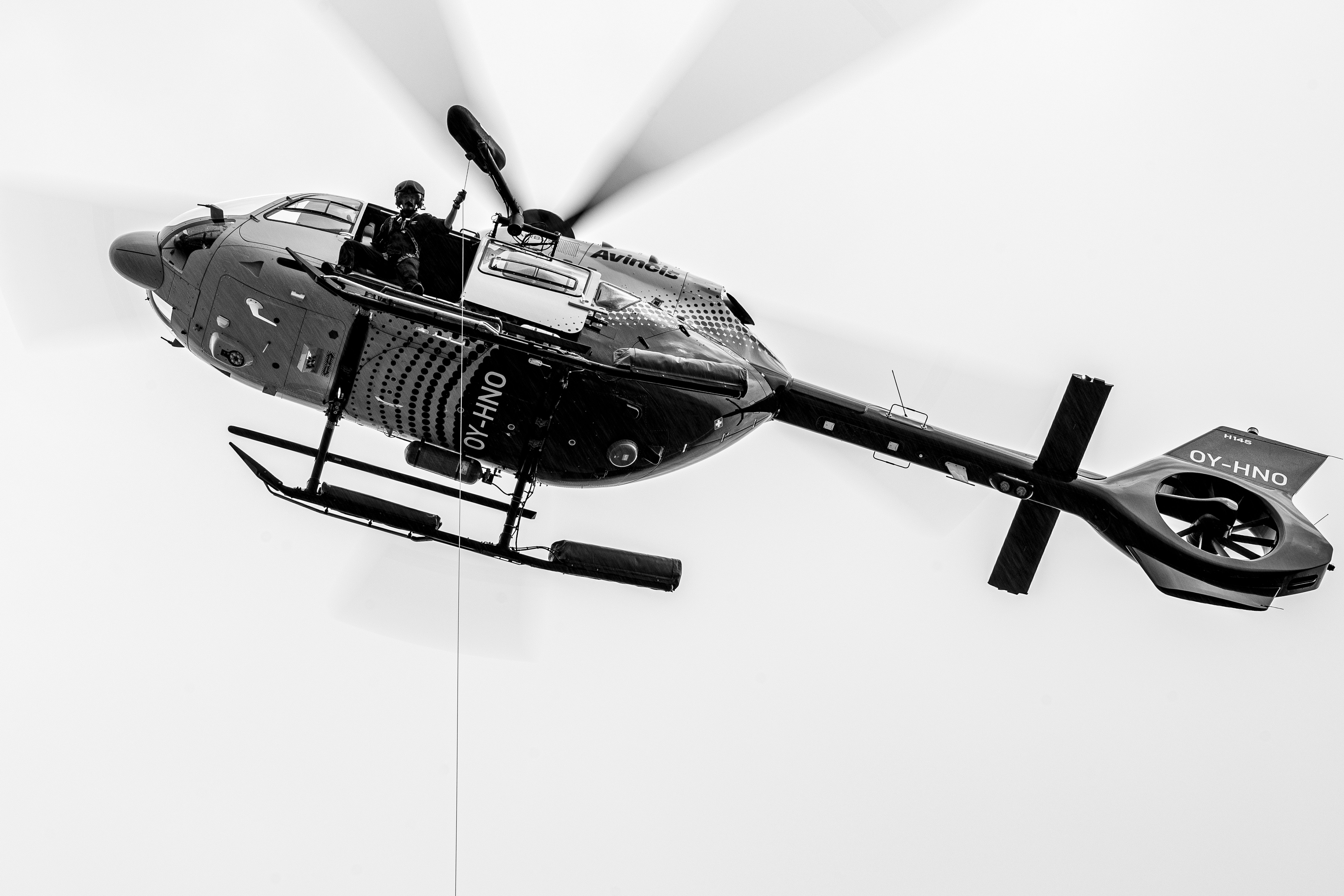 H145 Hoist Operator performing a cable check on a 50m hoist. He checks the full length of the cable with a weight applied, applying a consistent tension on the cable to ensure longevity and safety of the equipment.