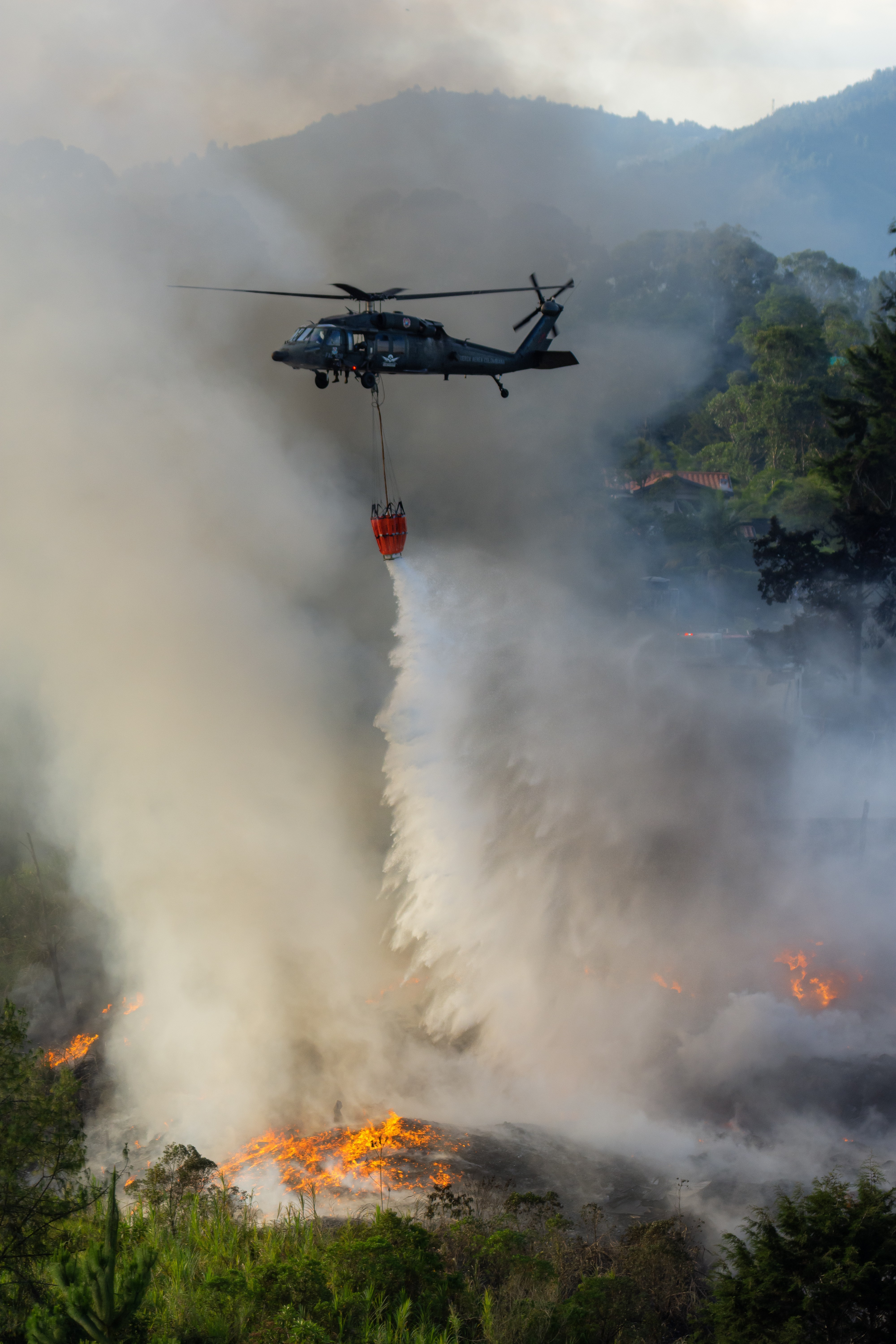 The Colombian Air Force´s ´Angel´ helicopter carrying out arduous work amidst mountains and tall trees supporting firefighting efforts in the city of Rionegro, Antioquia, Colombia.