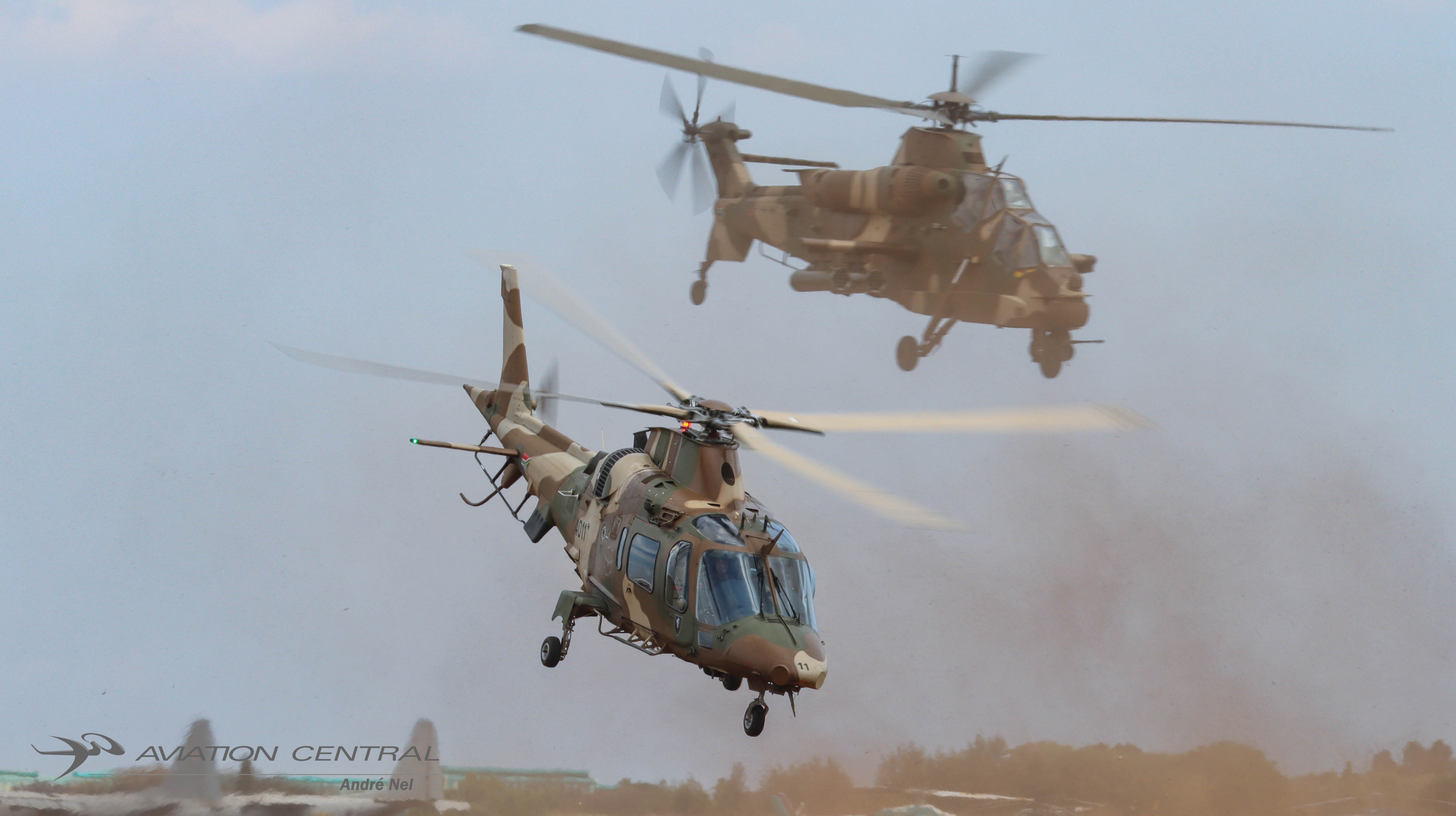 A South African Air Force A109 of 17 Squadron and Denel Rooivalk of 16 Squadron emerge through the dust during the Mini War demonstration at Africa Aerospace and Defence 2026, AFB Waterkloof, South Africa.