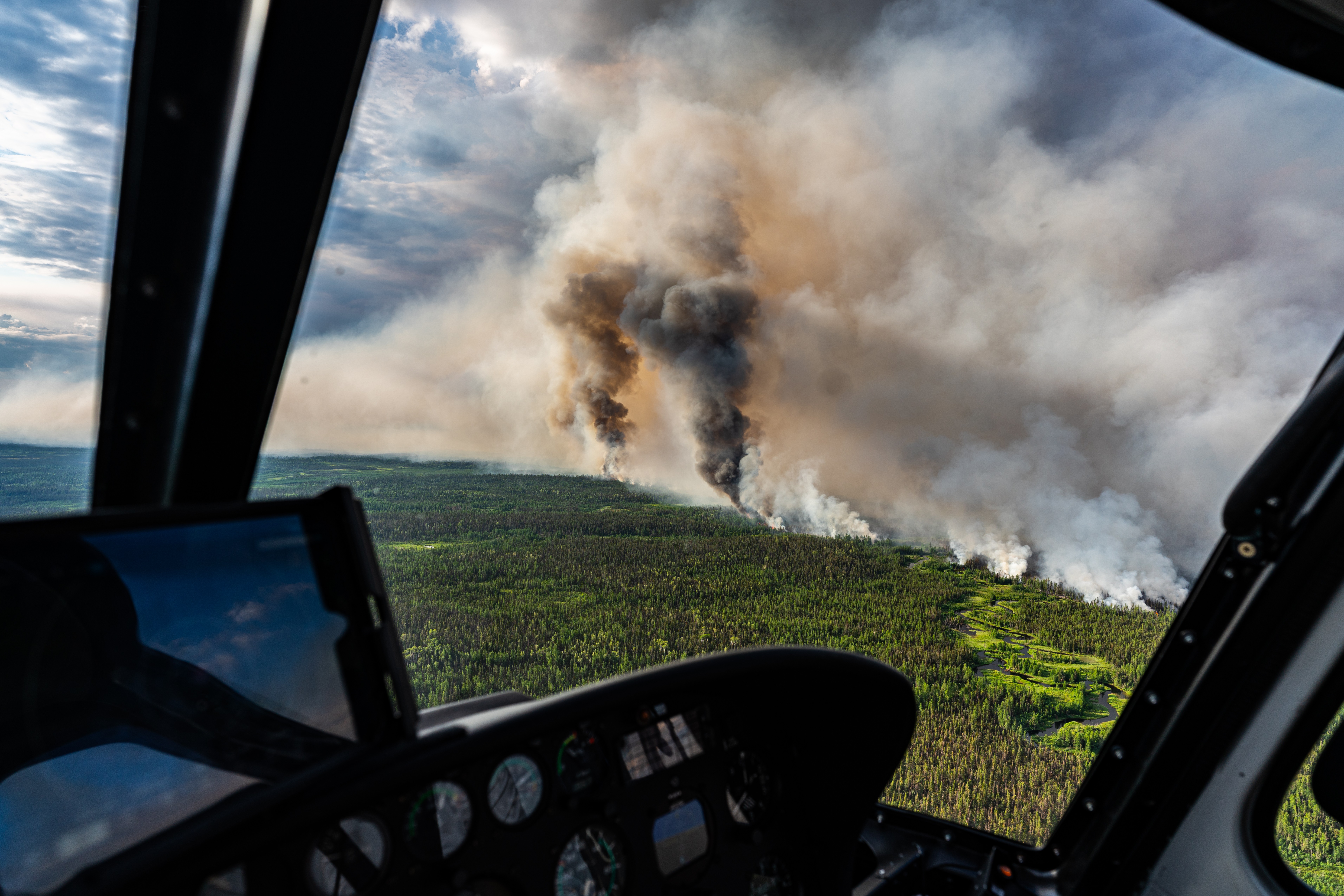 Assessing out of control wildfire. Black columns of smoke indicating increasing wildfire behaviour. Views from an Astar in northern Manitoba, Canada.