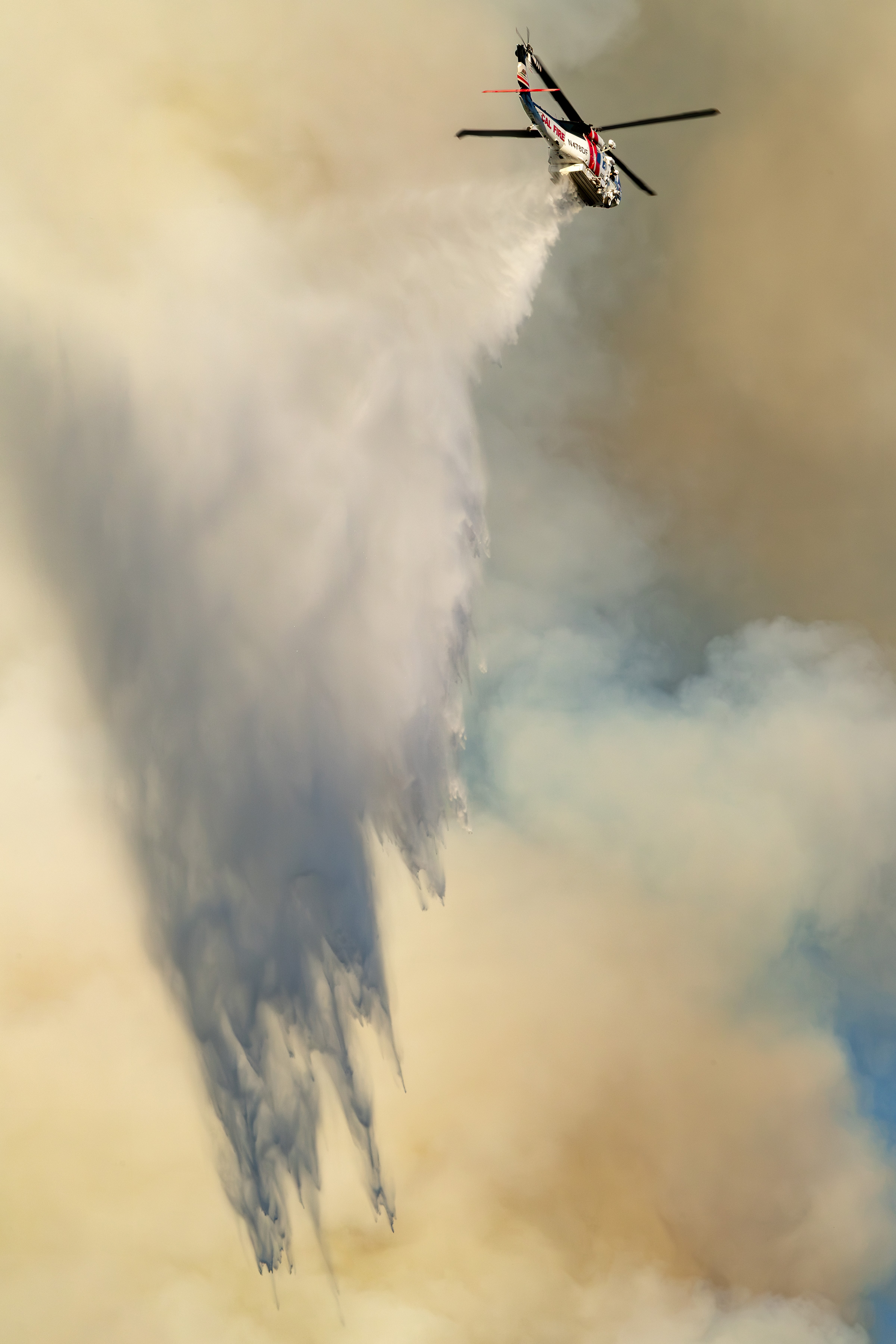 The Green Fire started off of CA-38 in a valley between two large mountains in the San Bernardino National Forest and it was moving up the back side of the mountains. Cal Fire’s Firehawk dropped high on the top of the mountain to prevent the fire from cresting over. I loved the soft pastel colors and how the falling water interacted with the smoke-filled sky, which was reminiscent of a painting. I quickly turned my camera to get a vertical photograph for a more unique composition.