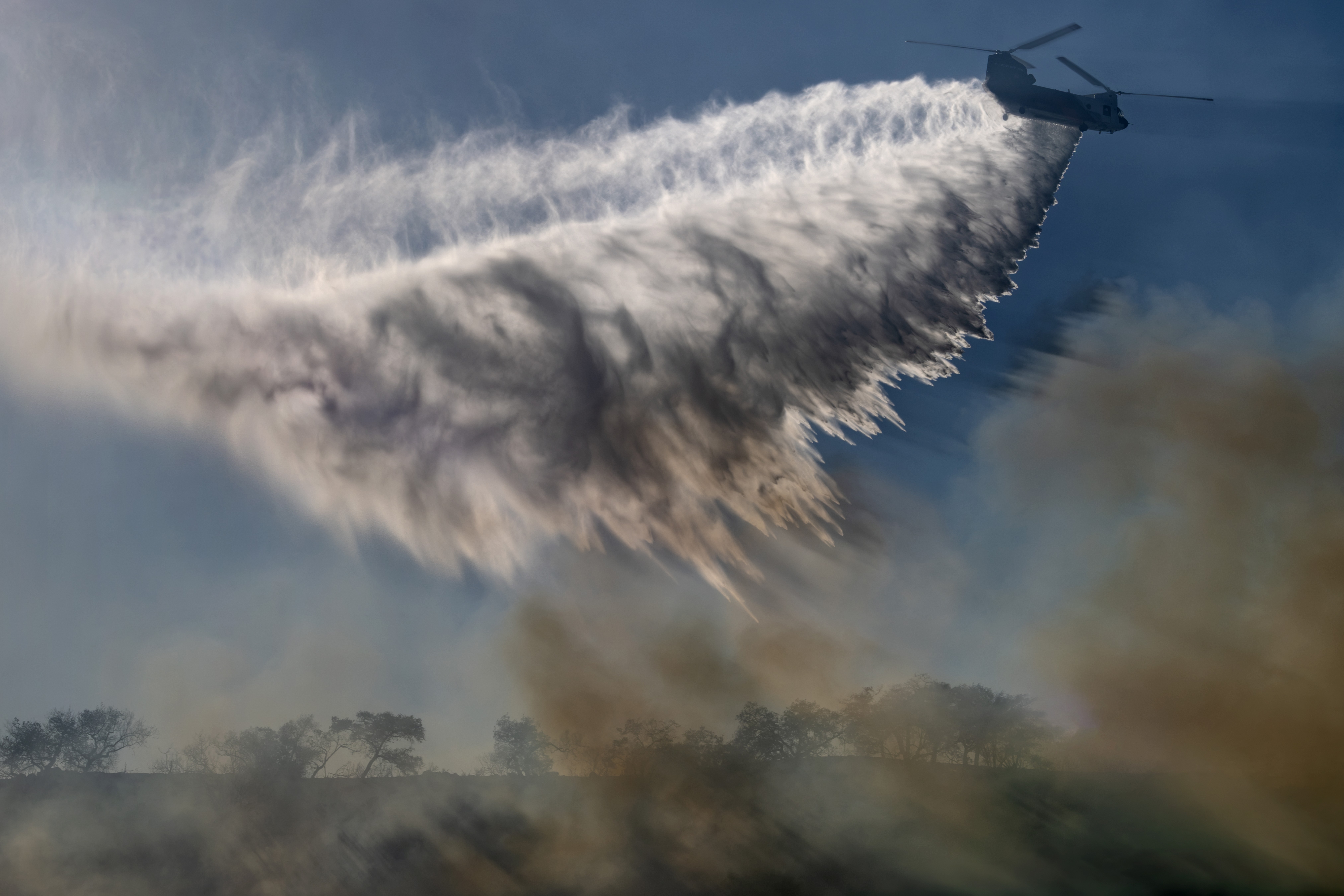 Driving out of the Volcano Fire in Murrietta, California, various aircraft started dropping in a hilly area on the outskirts of the fire.  The backlit image of Cal Fire's Firehawk dropping water with the rising smoke, produced a really interesting photograph. Backlit pictures can really add dimension to falling water and rising smoke