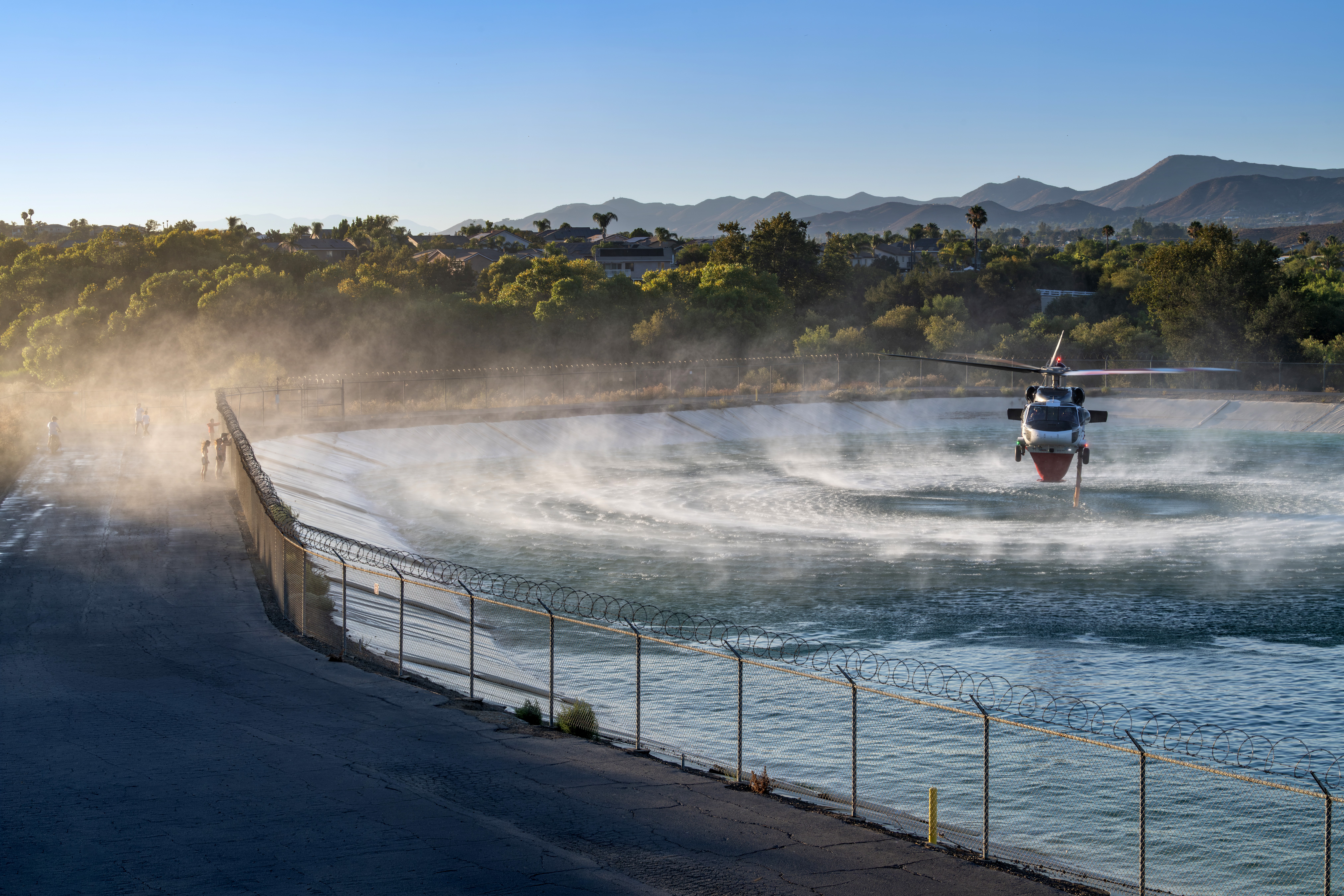 The kids on the far left in the picture took advantage of the 100º heat by getting soaked from the spay of PJ's UH-60A picking water for the Volcano Fire. This reservoir was near Cole Canyon in Murrieta, California. The warm late afternoon light added to the dynamics of this image.