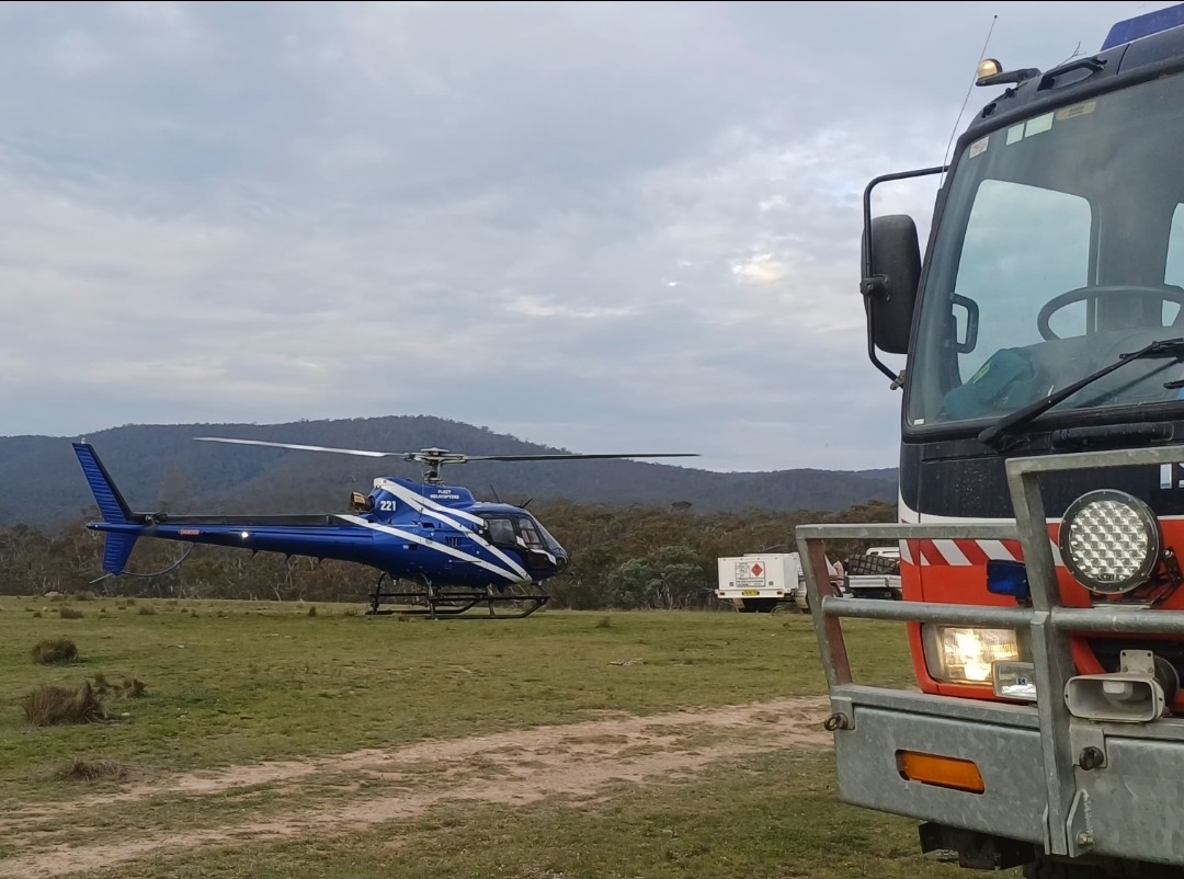 Where earth meets sky—ground crews and aerial support pause between operations during a National Parks hazard reduction burn, showcasing the teamwork behind bushfire preparedness.