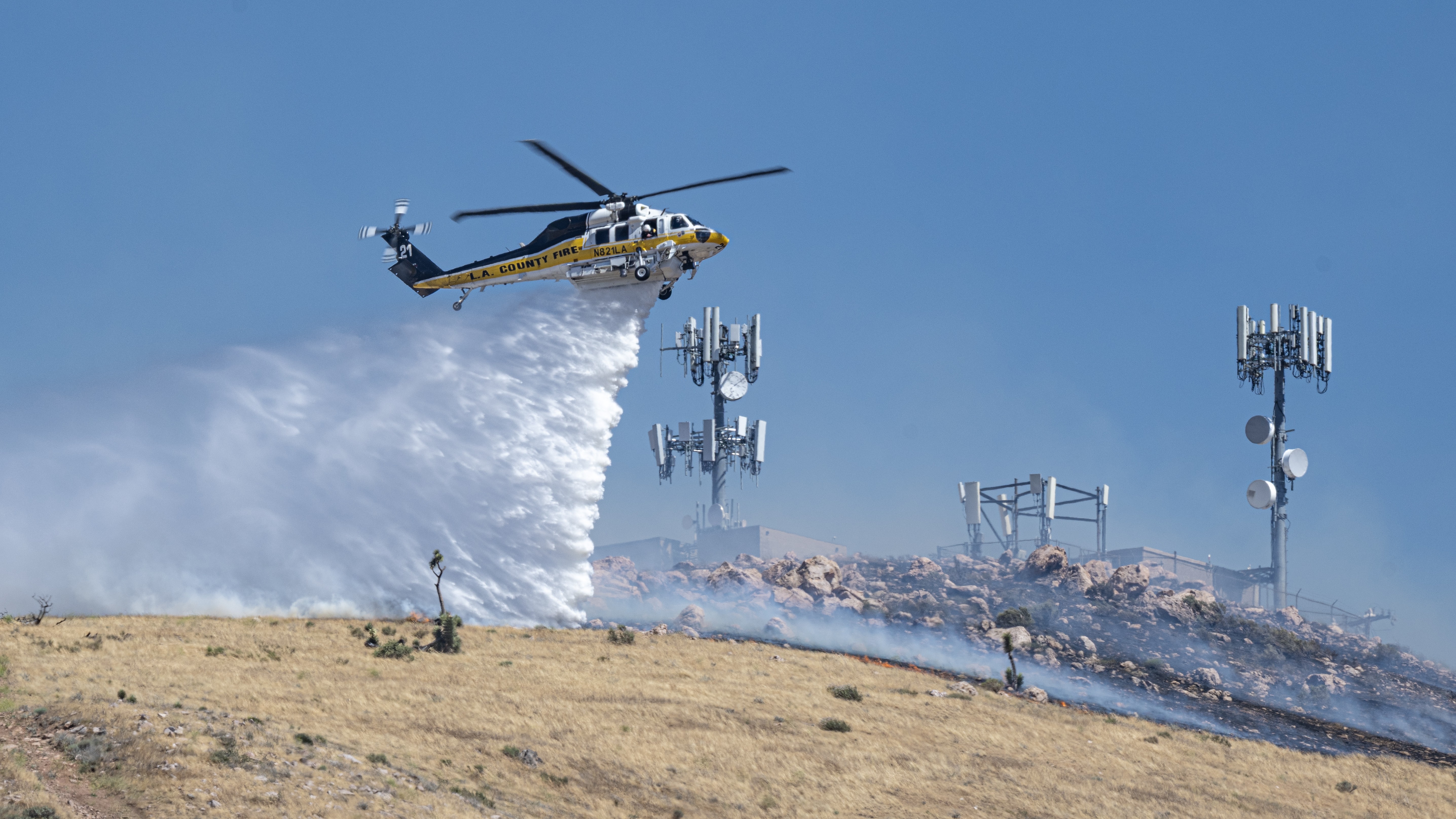Los Angeles County Fire Department's Copter 21 makes a water drop to protect infrastructure during the Lemon Incident in Palmdale, California on June 13, 2026