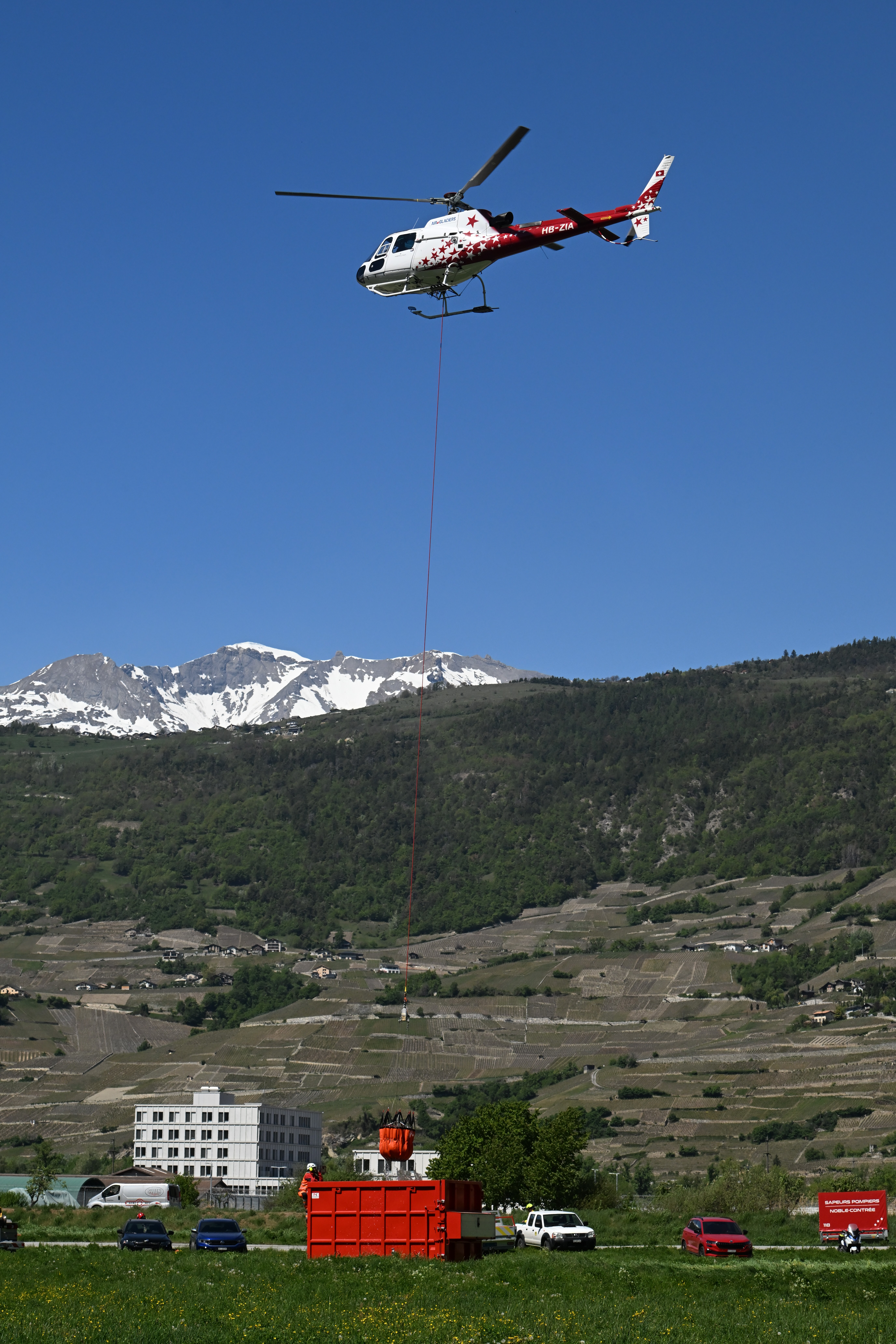 feux de forêt en Valais (CH) B3 Ecureuil d'Air-Glaciers HB-ZIA remplissage du Bambi depuis une benne d'un camion pompier. Nikon Z8+adaptateur et 70-200mm f2.8