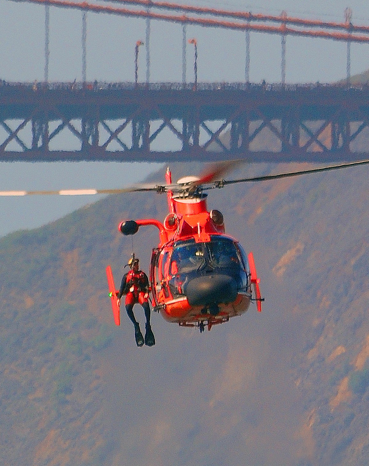 U.S. Coast Guard rescue  diver sits poised searching over the water in the San Francisco Bay a water after a call for rescue of a i water person.