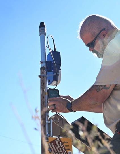 Mark Bean, 377th Air Base Wing Plans and Programs range operations officer, is installing a N5 Wildfire Sensor on Kirtland Air Force Base, N.M., Oct. 23. The N5 Sensor can detect smoke at distances of five miles and can detect fires comparable to high end lab devices. (U.S. Air Force photo by Senior Airman Ruben Garibay)