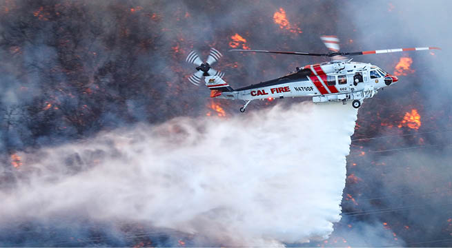 A helicopter is flying over a forest fire, spraying water to extinguish the flames. AI generated content