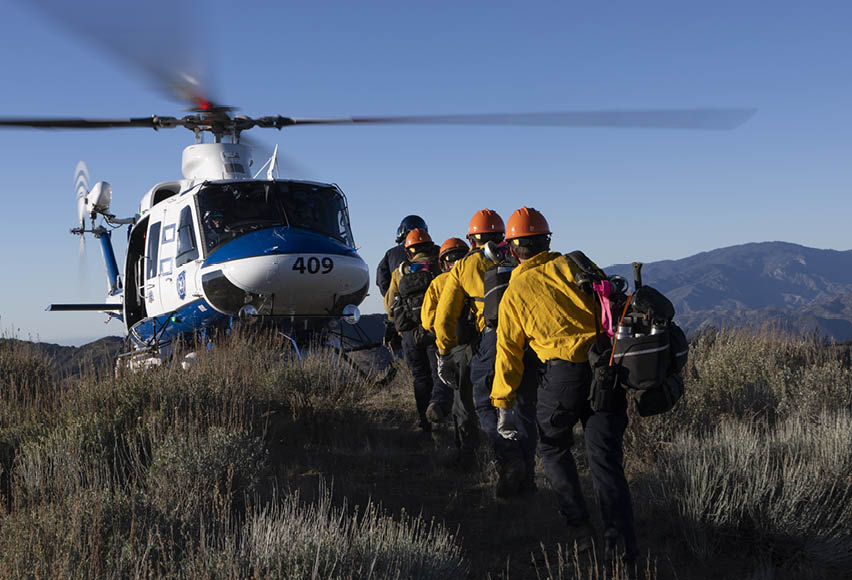 A group of people wearing orange vests are walking in front of a helicopter. AI generated content