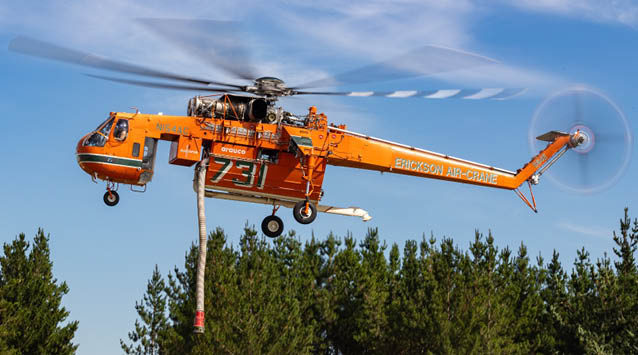 A large orange helicopter with a red post underneath it is flying in the sky. AI generated content