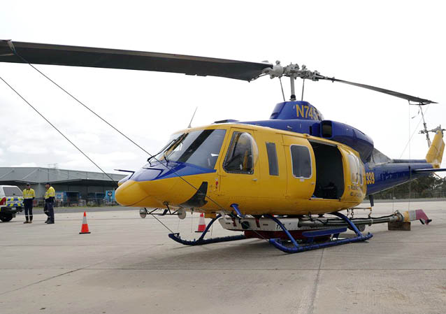 A yellow and blue helicopter is parked on the ground with its landing gear down. AI generated content