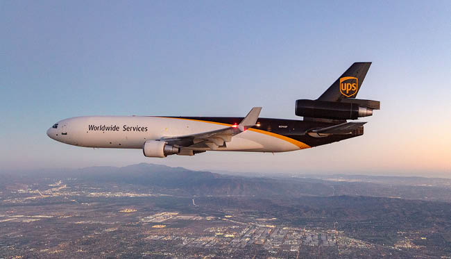 A large UPS airplane is flying over a city with a sunset in the background. AI generated content
