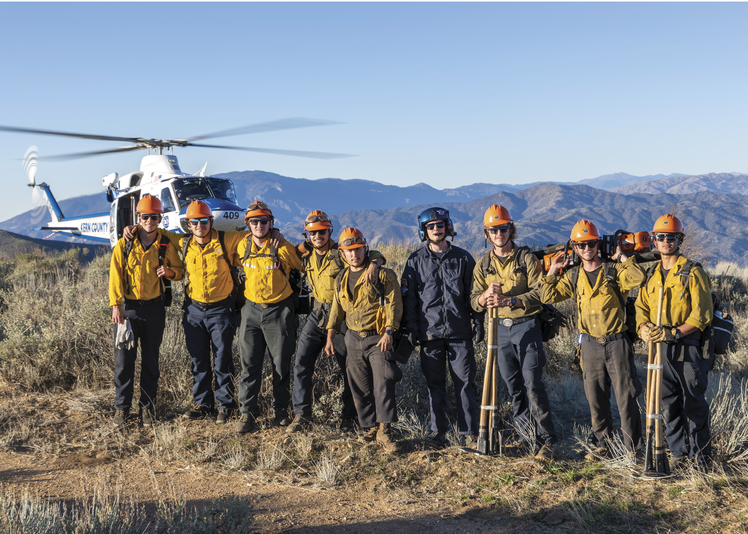 A group of men wearing orange hats and yellow jackets pose for a picture in front of a helicopter. AI generated content