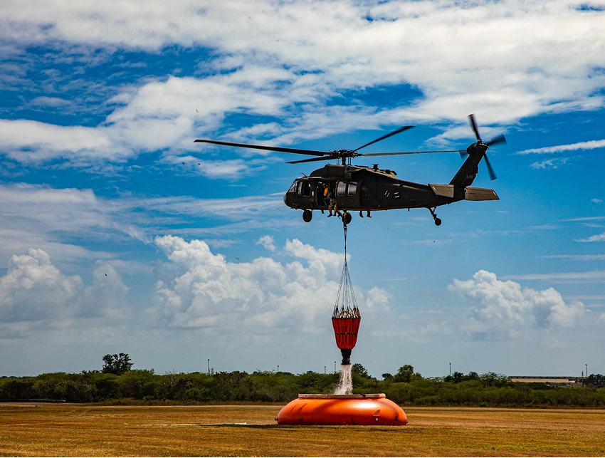 A helicopter is lifting a red object, possibly a rescue device, from the ground. AI generated content