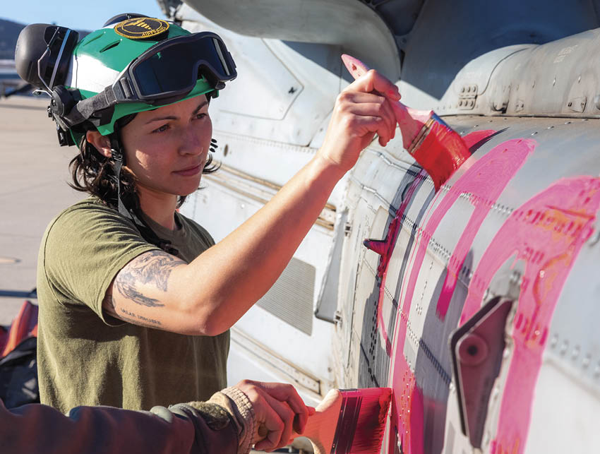 A person wearing a helmet is touching a jet with a red paint marker. AI generated content