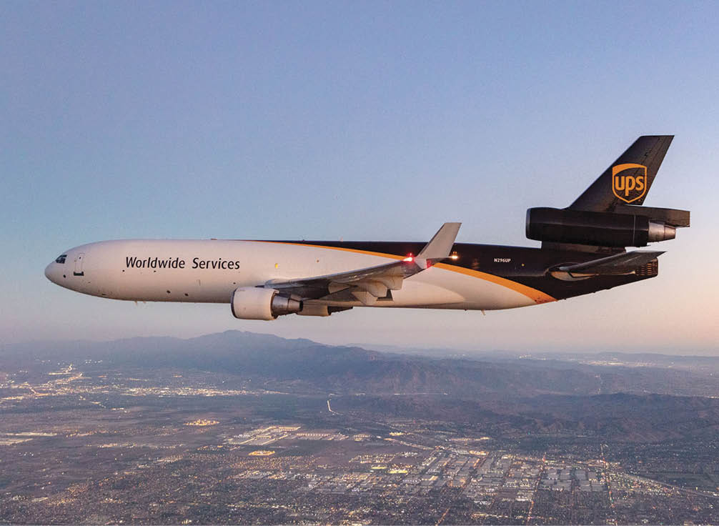 A large UPS airplane is flying over a city with a sunset in the background. AI generated content