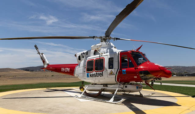 A red and white helicopter with a large propeller is parked on a yellow circle. AI generated content