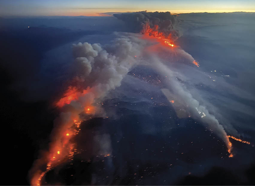 A large fire is burning in the distance, with smoke billowing upwards. The fire is visible from a distance, and it appears to be growing in size. AI generated content