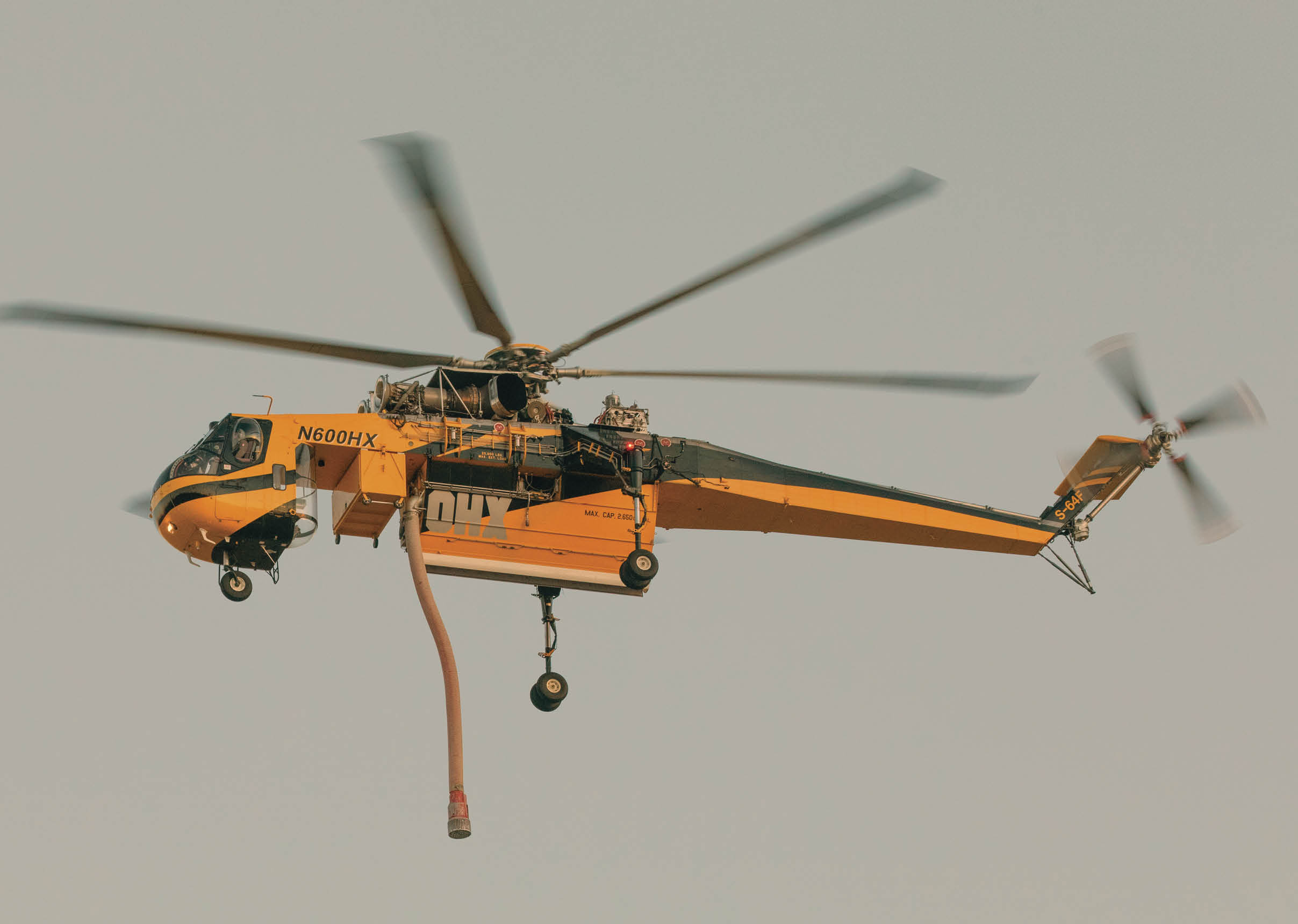 A yellow helicopter is flying in the air with a person hanging from a rope. AI generated content