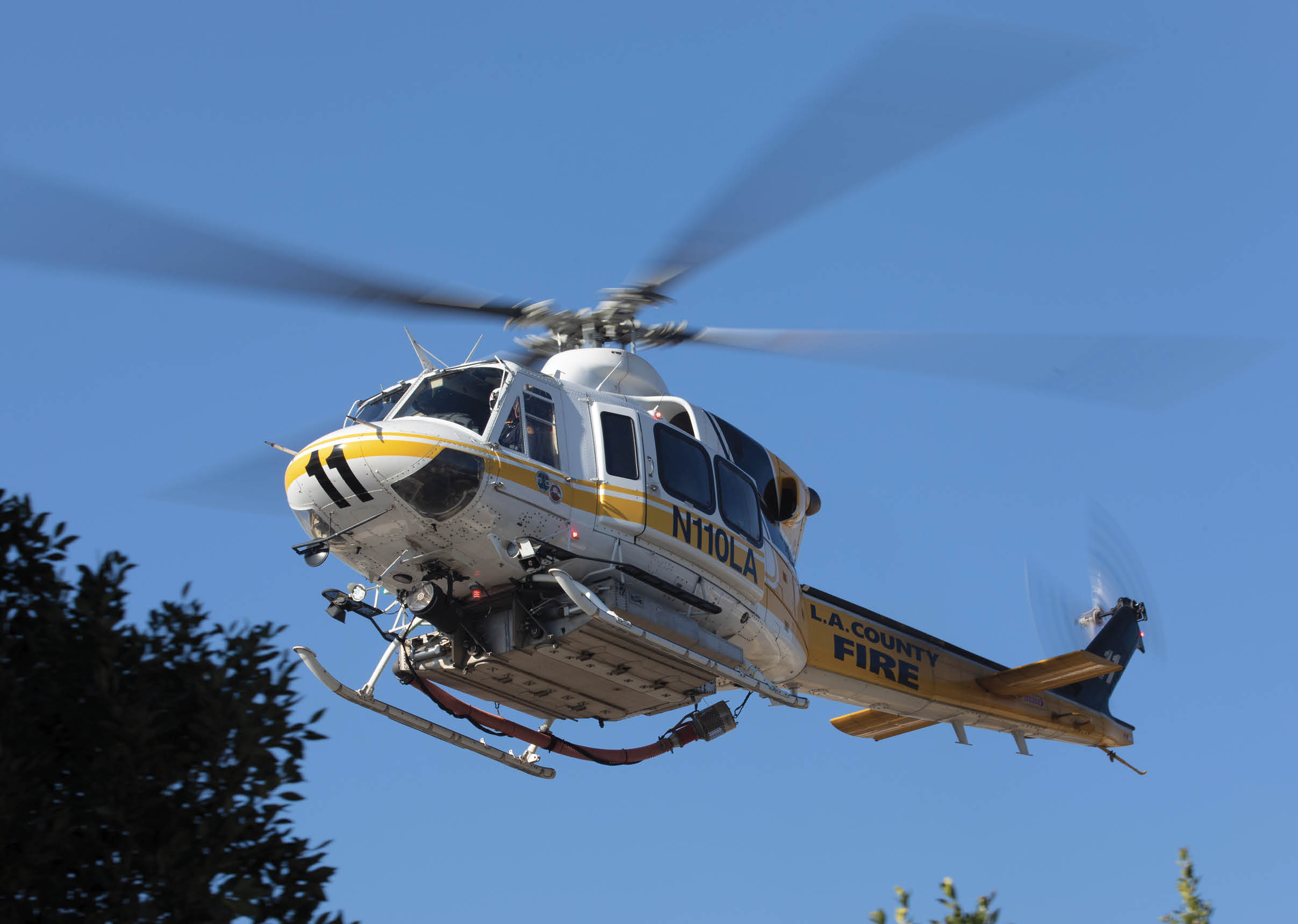 A yellow and black helicopter with the words “Cal Fire" on the side is flying in the sky. AI generated content