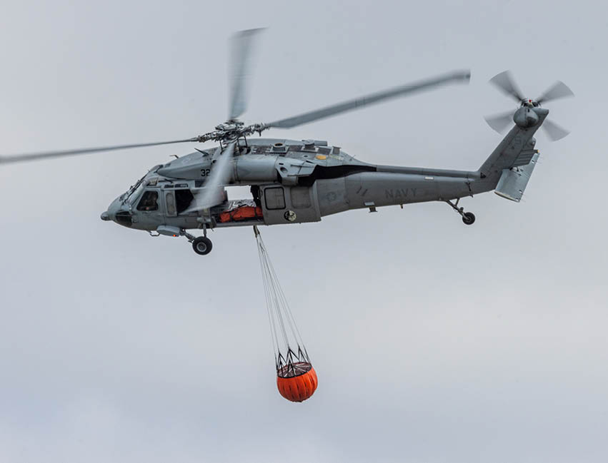 A helicopter is flying in the air with a red object hanging from it. AI generated content