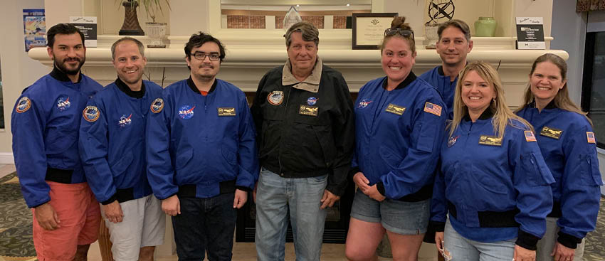 A group of people wearing blue jackets pose for a picture in front of a fireplace. AI generated content