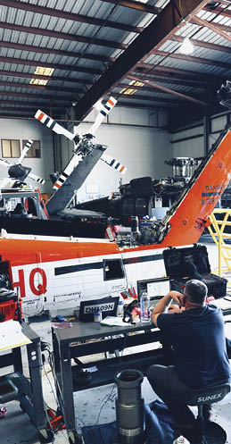 A man is working on a helicopter in a hangar. AI generated content