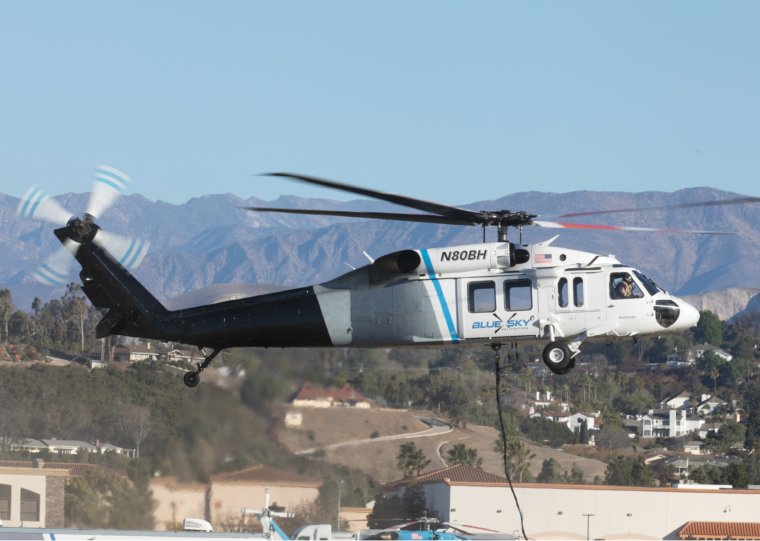 A helicopter is flying over a city with mountains in the background. AI generated content