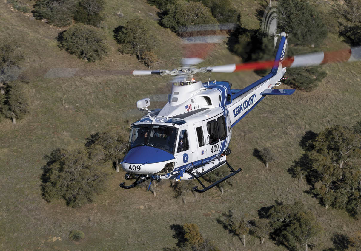A helicopter is on the ground in a field with a person standing nearby. AI generated content