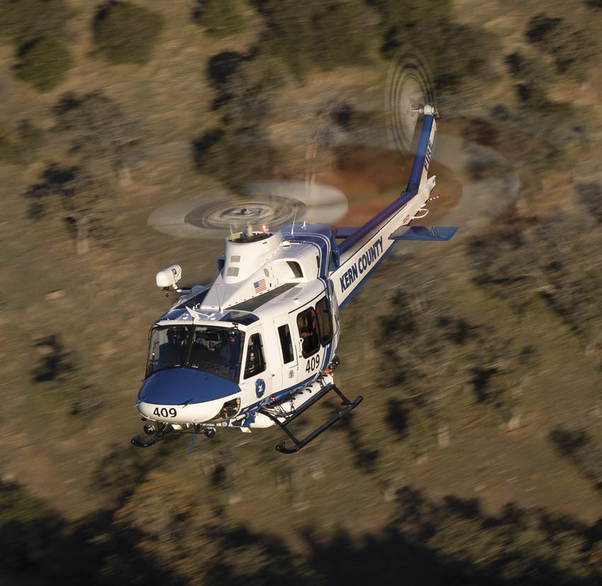 A helicopter is flying over a field with a blue and white body. AI generated content