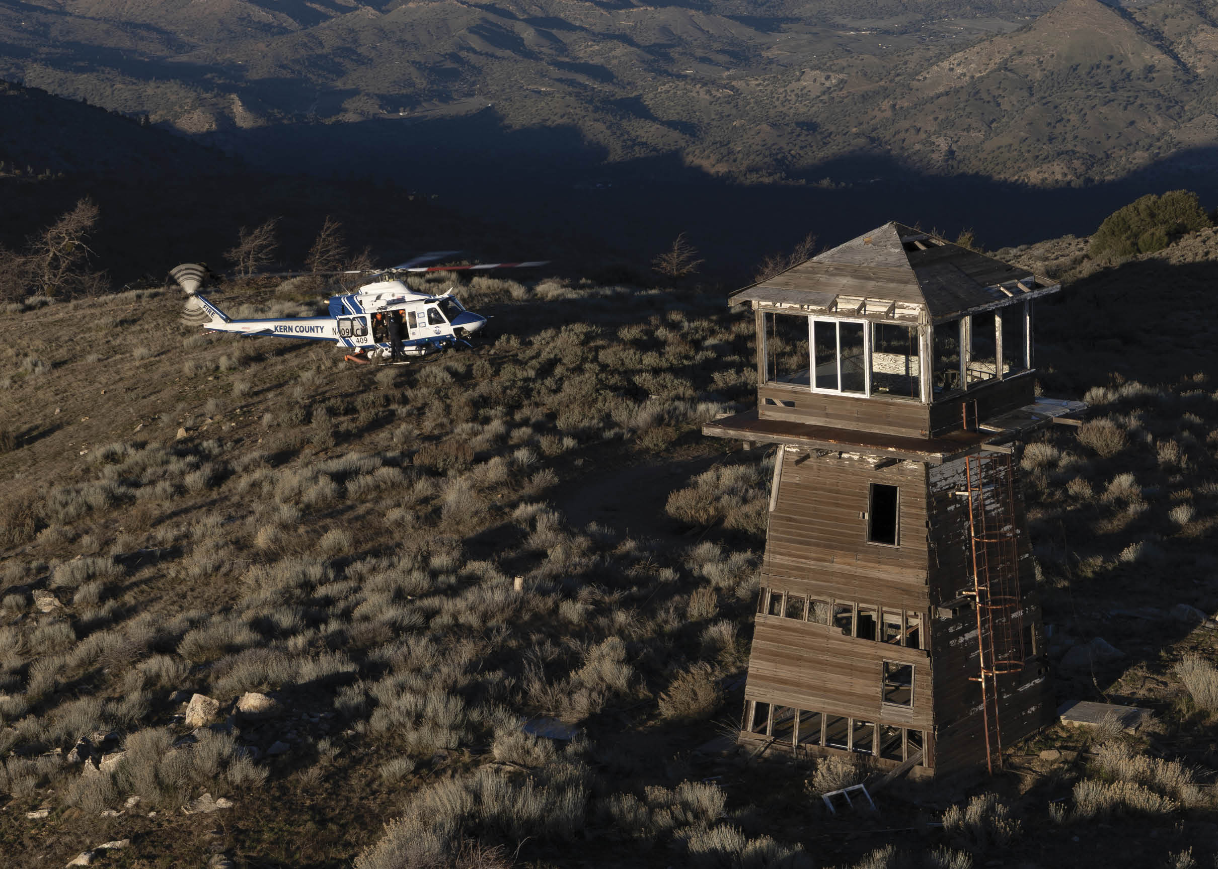 A helicopter is flying over a lone tower in a field. AI generated content