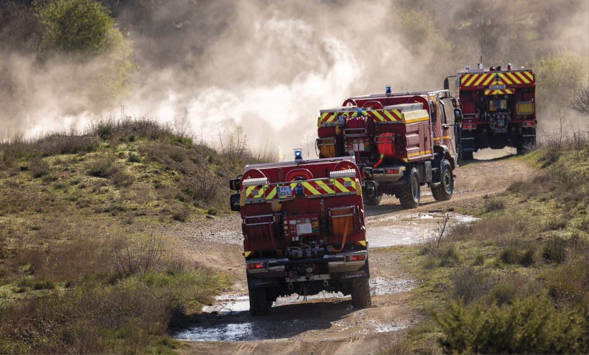 Three fire trucks are driving down a dirt road. AI generated content