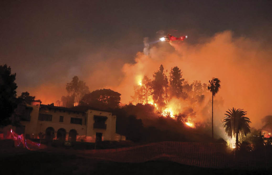 A fire is burning in the distance, with flames reaching high into the sky. A helicopter is flying above the scene, possibly trying to help with the firefighting efforts. The fire is located near a house, and there is a fence nearby. AI generated content