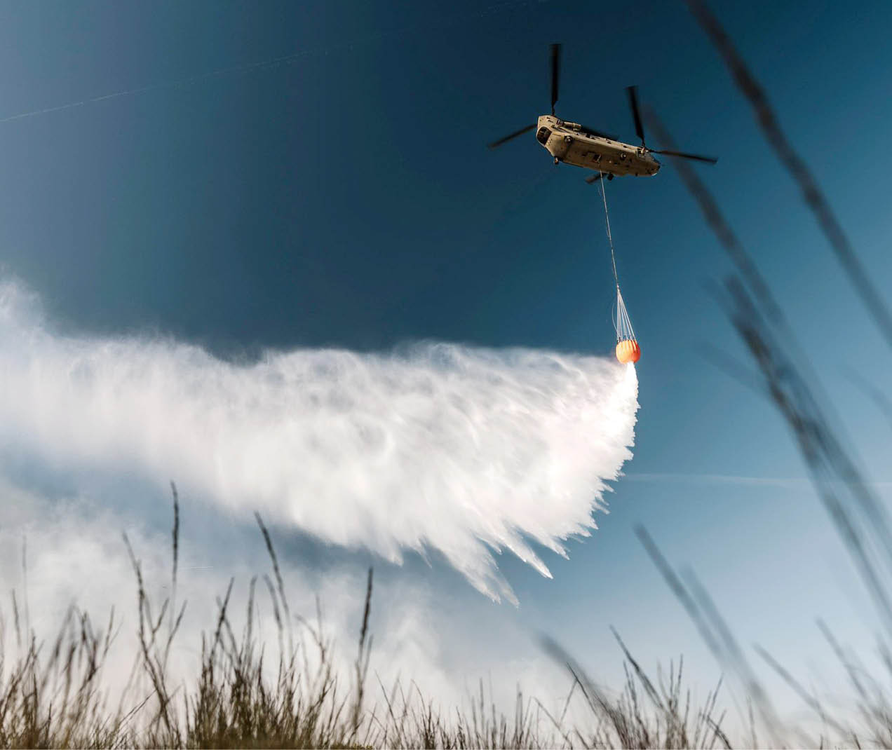 Four firefighters are standing in a field, watching a plane flying through the sky. AI generated content