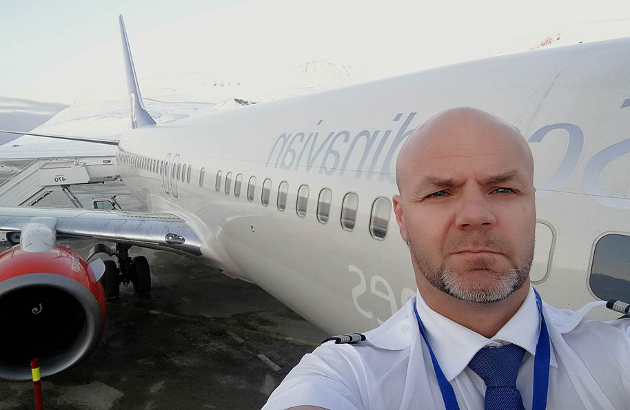 Two airplanes are parked on a runway, one is yellow and the other is white. The sun is setting in the background, casting a warm glow on the scene. AI generated content