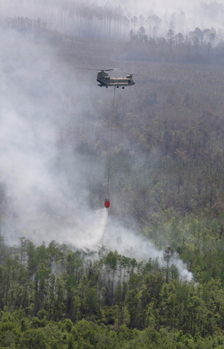 A helicopter is flying over a mountain range, dropping a red object. AI generated content