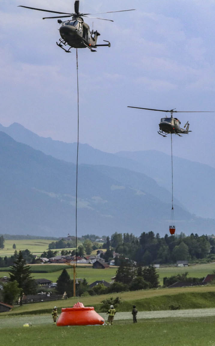 A helicopter is flying over a mountain range, dropping a red object. AI generated content