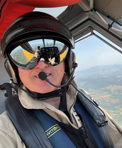 A man in a tan jacket stands in front of a yellow airplane. AI generated content