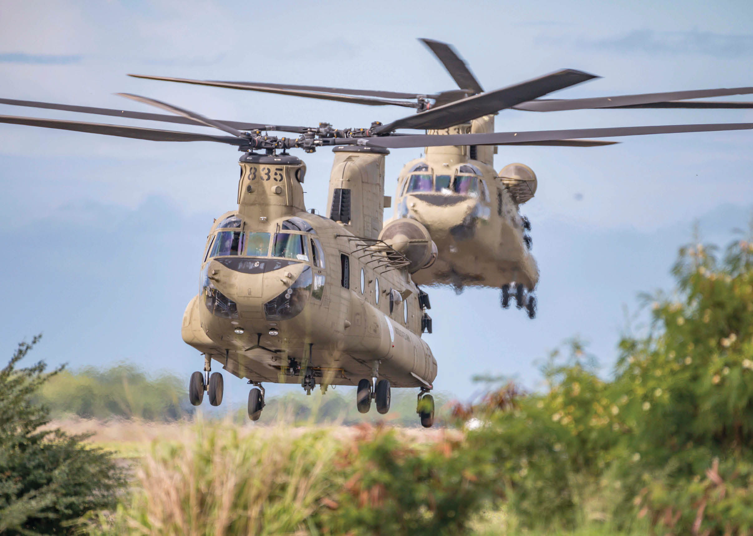 A pair of CH-47 Chinook helicopters from Company B, 1st General Support Aviation Battalion 211 Aviation, Hawaii National Guard (HING) loaded with Soldiers and equipment take off for transport to Maui and Kauai, April 13, 2020, Kapolei, Hawaii. Additional HING Soldiers have been activated to assist with missions on all the neighbor islands. (US Army National Guard photo by Sgt. John Schoebel)