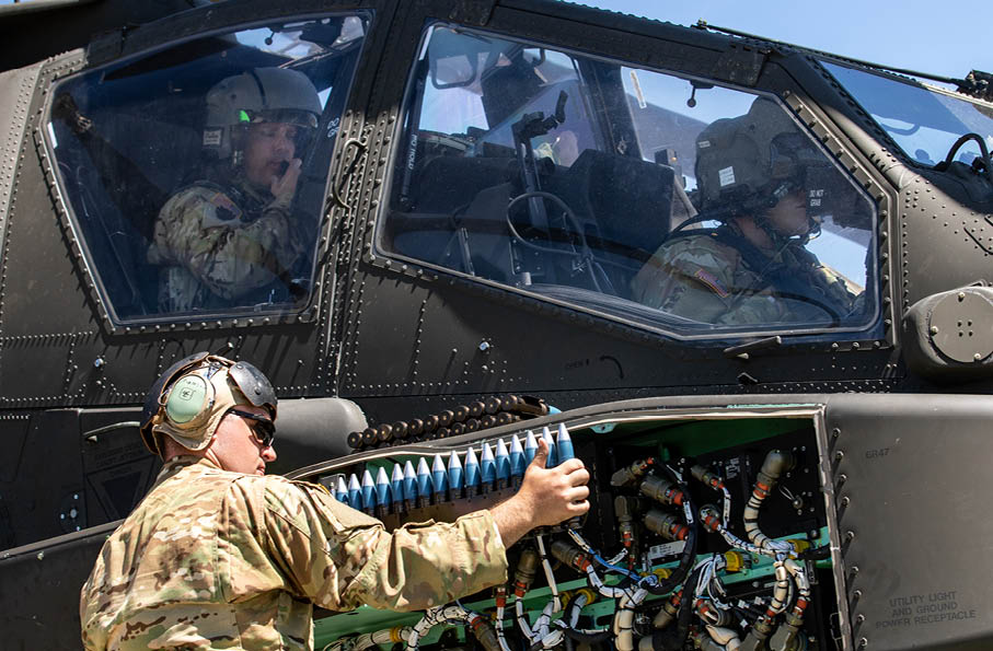 U.S. Army Cpl. Nathaniel Miller (bottom left), an AH-64 Armament/Electrical/Avionic Systems Repairer with the 1st Attack Battalion, 1st Aviation Regiment, 1st Combat Aviation Brigade, 1st Infantry Division, loads 30mm chain gun rounds into an AH-64E Apache helicopter during Apache gunnery at the Digital Multi-Purpose Range Complex, Fort Riley, KS., on August 11, 2022. The aerial gunnery gave Army aviators and ground crews the opportunity to train and increase their proficiency on refit operations for the Apache helicopter. (U.S. Army photos by Staff Sgt. Keegan Costello, 19th Public Affairs Detachment.)