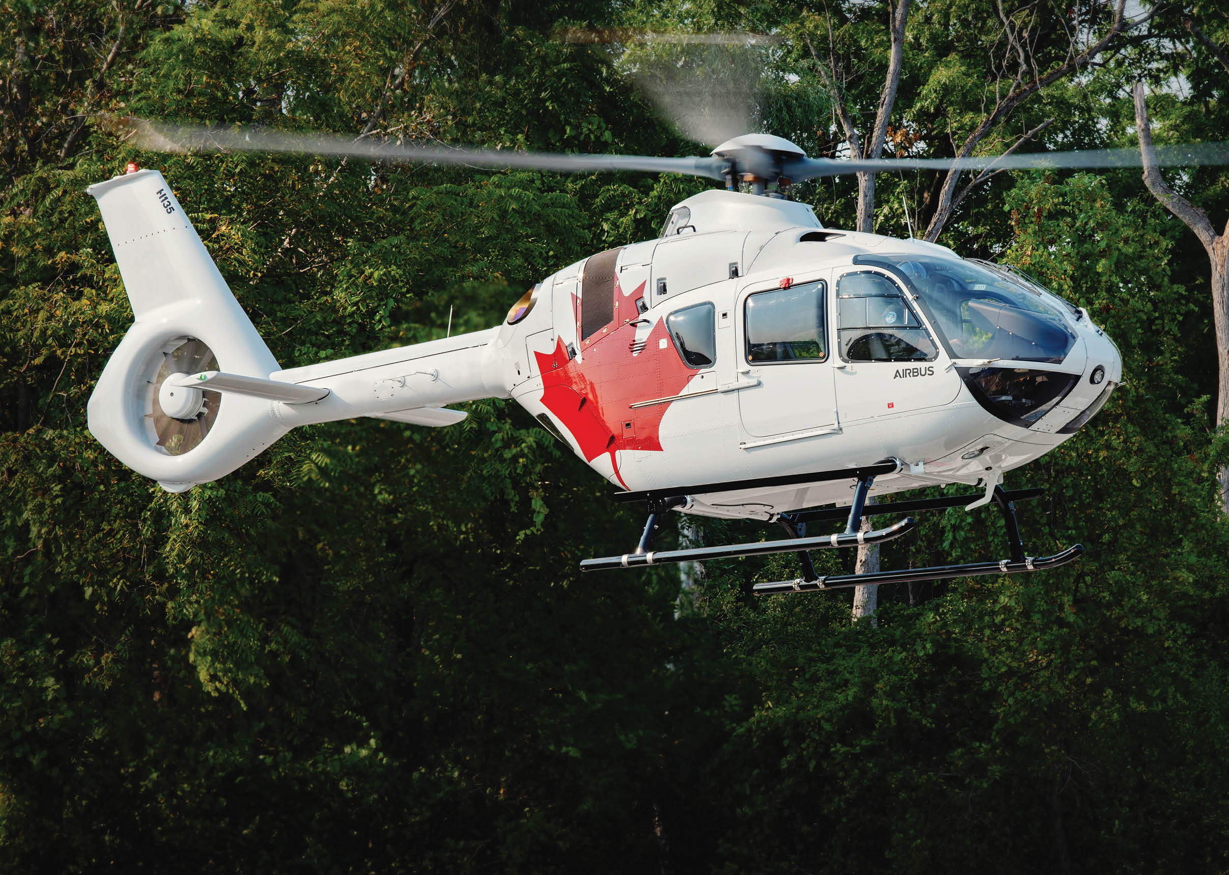A helicopter with a Canadian flag painted on it is flying over a forest. AI generated content