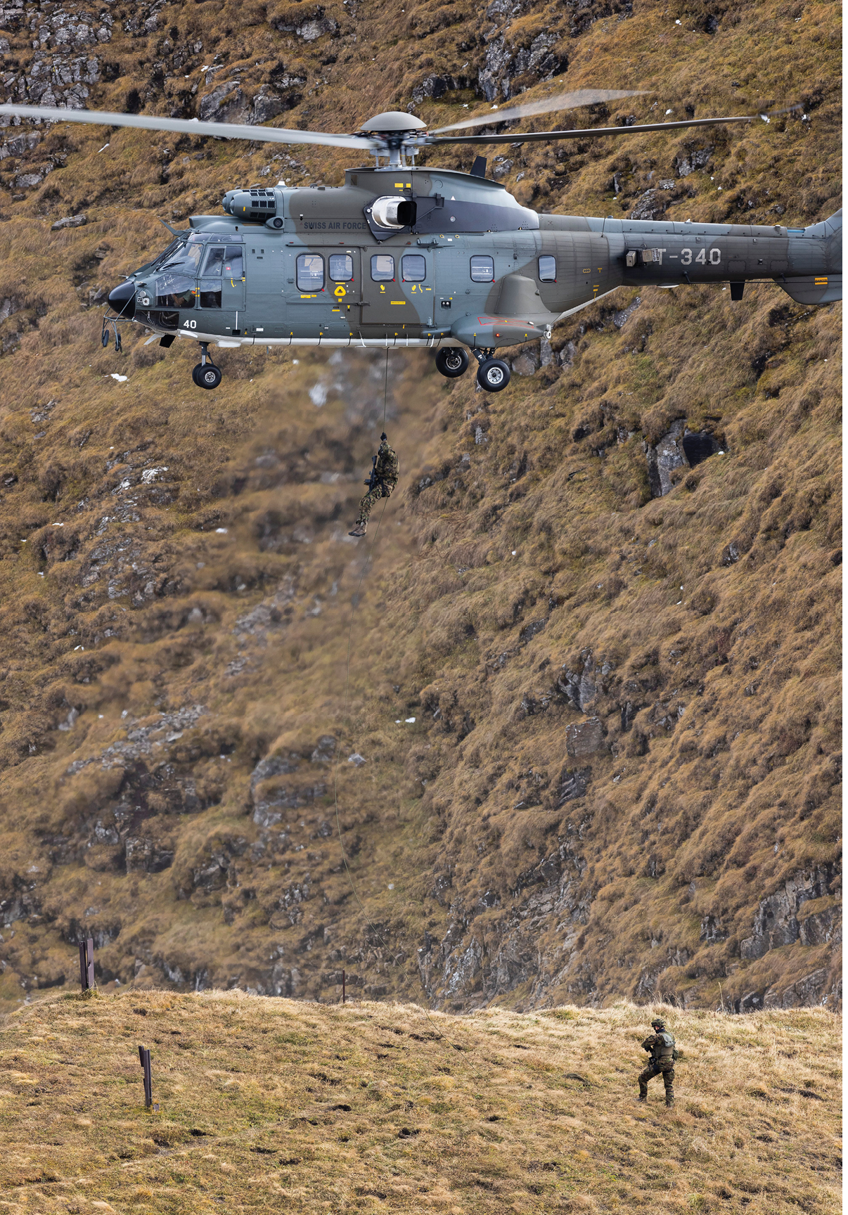 A helicopter is flying over a grassy hillside with a person standing below it. AI generated content