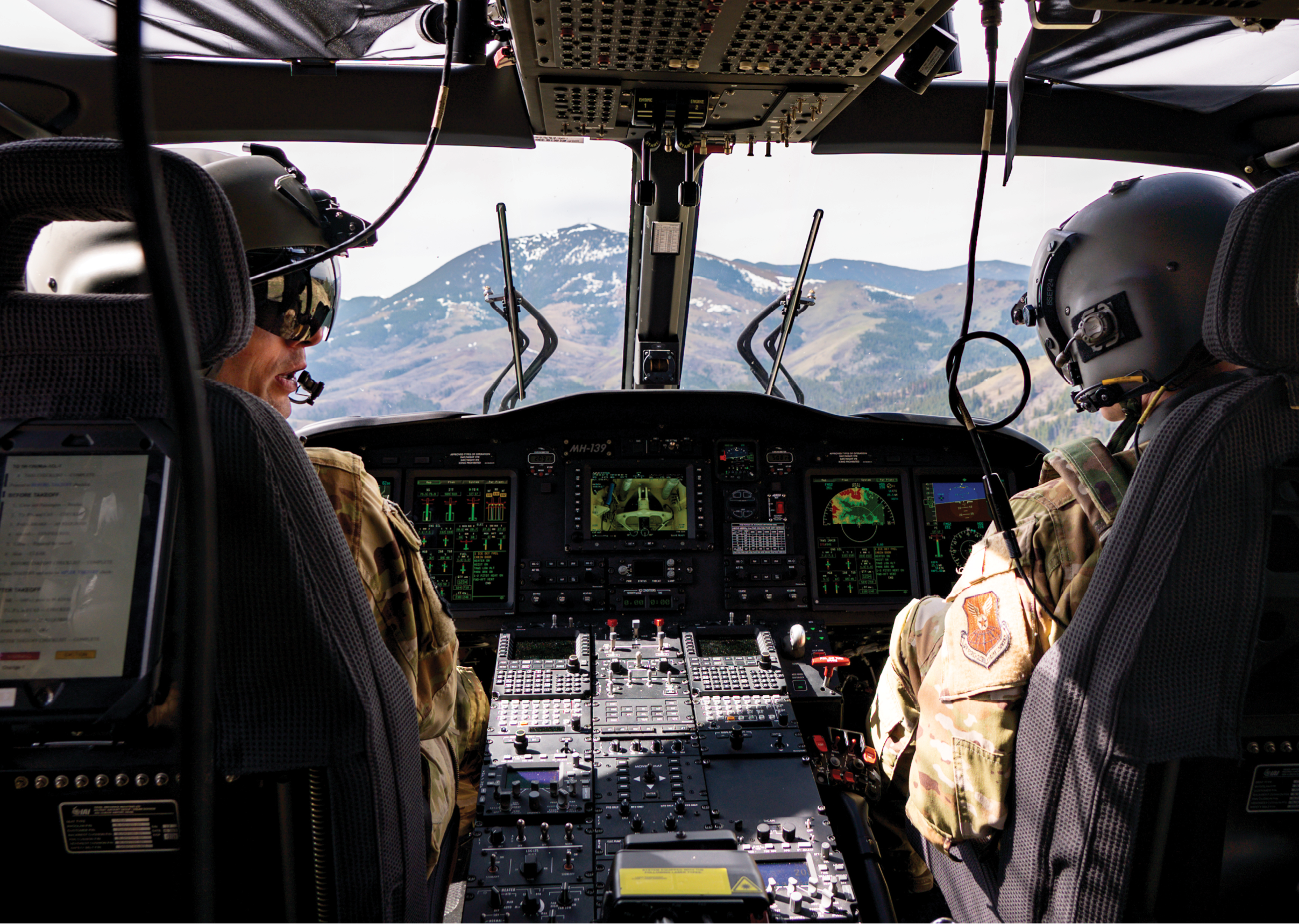 Two pilots are in a helicopter cockpit, flying over a mountain range. AI generated content