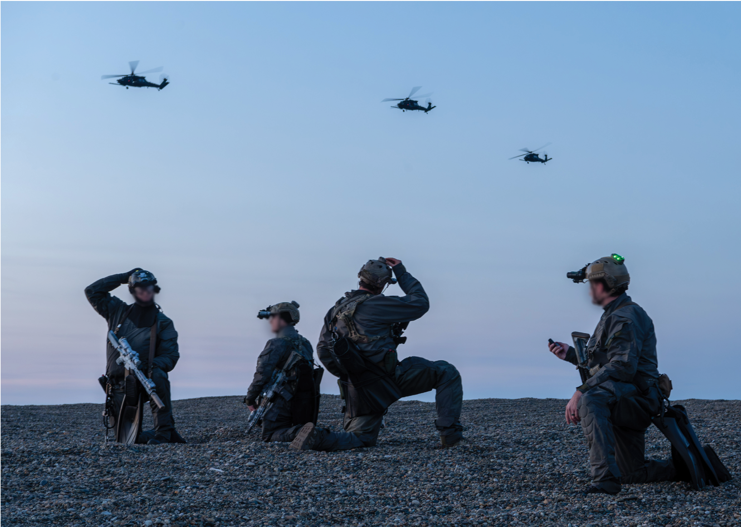 Four men in military uniforms are kneeling on a beach, looking up at the sky. They are equipped with helmets and weapons, and appear to be observing a helicopter flying overhead. AI generated content