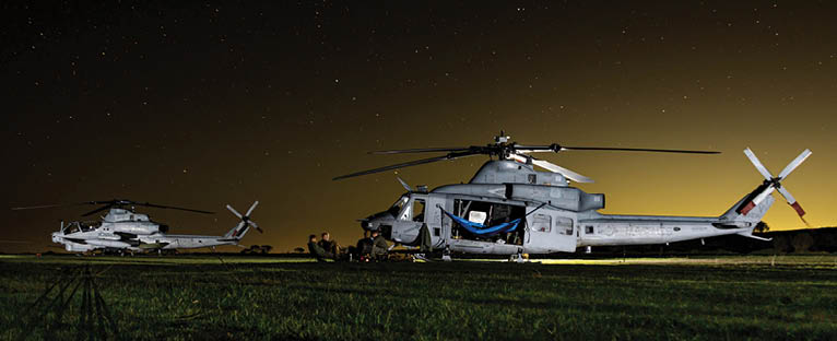 Three helicopters are parked on a grassy field at night. AI generated content