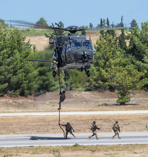 Three soldiers are walking on a road, with one of them holding onto a helicopter. The helicopter is in the process of landing, and the soldiers are likely preparing for a mission or returning from one. AI generated content