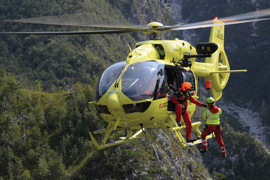A yellow helicopter is flying over a mountain with a man hanging from a rope. AI generated content