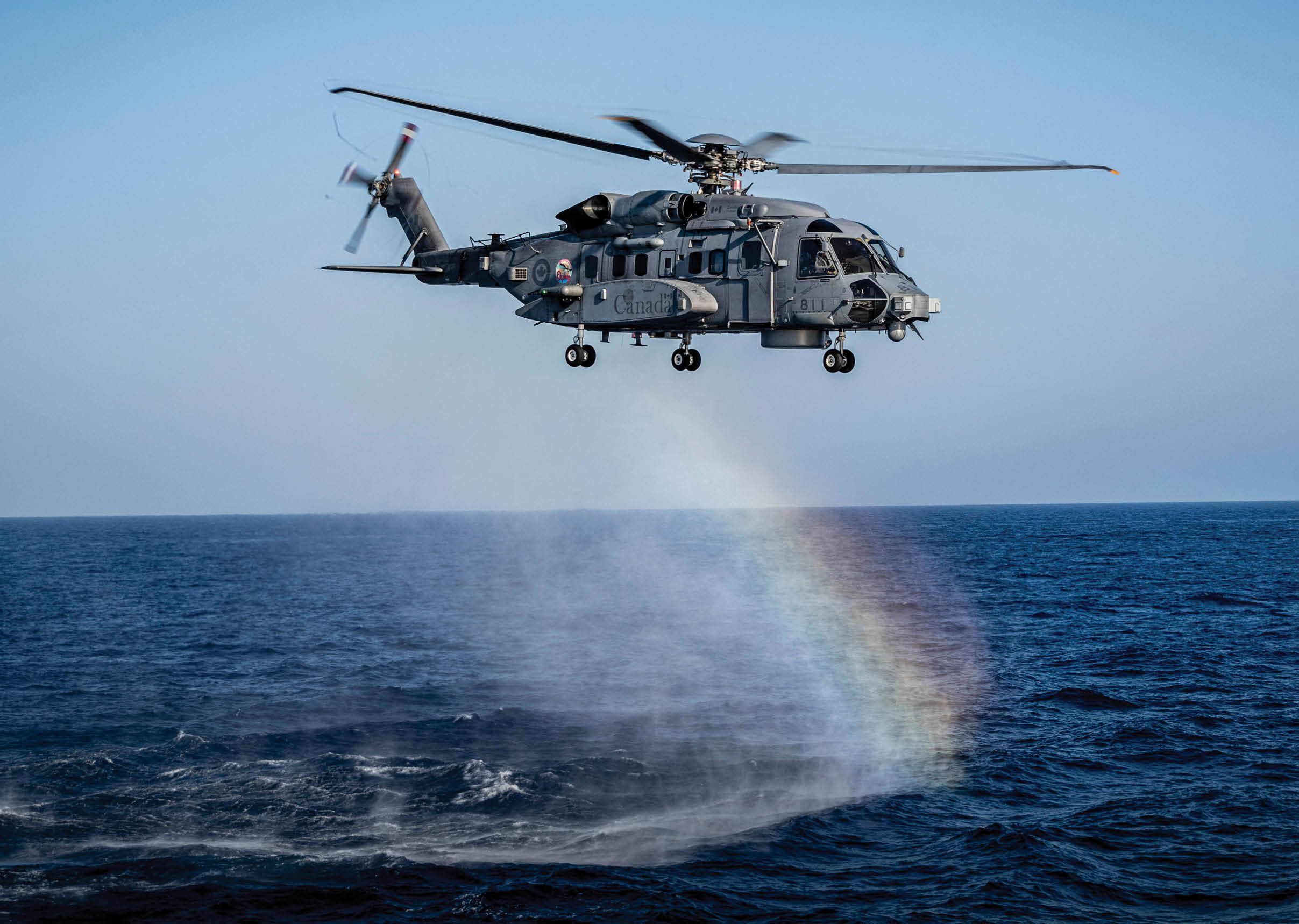 A helicopter is flying over the ocean, leaving a rainbow in its wake. AI generated content