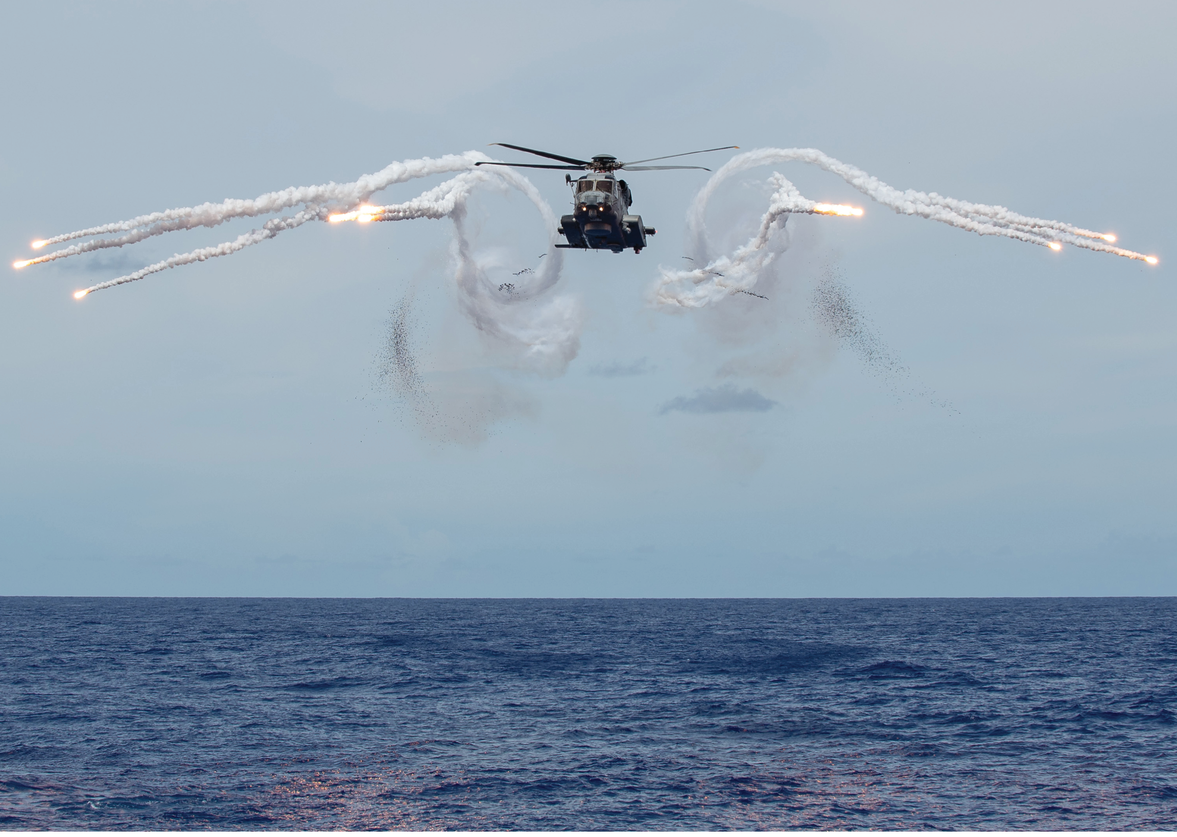 A helicopter is flying over the ocean, leaving a trail of smoke behind it. AI generated content
